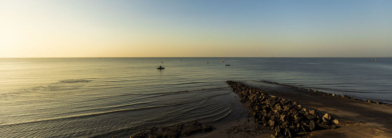 Scenic view of beach against clear sky during sunset