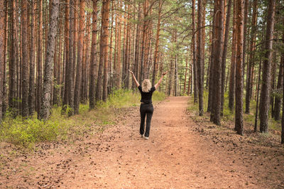 An adult woman joyfully raised her hands up, restoration of health and psyche, forest baths