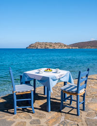 Deck chairs on beach against clear blue sky