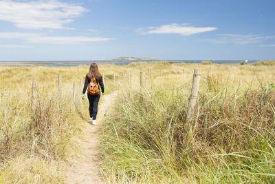 Rear view of woman standing on field against sky