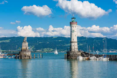 Lighthouse on building by sea against sky