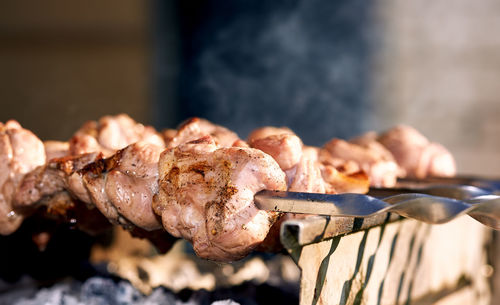 Close-up of meat in skewer on barbecue at back yard