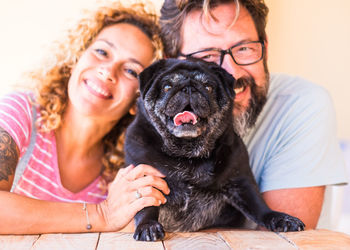 Portrait of couple with dog sitting by table