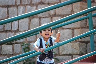 Portrait of happy boy standing by railing