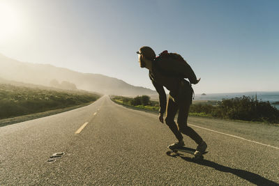 Full length of man skateboarding on country road