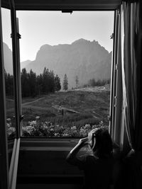 Rear view of little girl looking through window at home