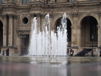 People at fountain of building