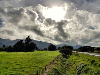 Scenic view of grassy field against cloudy sky