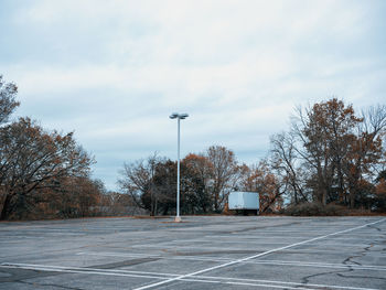 Empty road by trees against sky