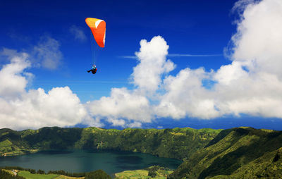 Low angle view of paragliding against blue sky