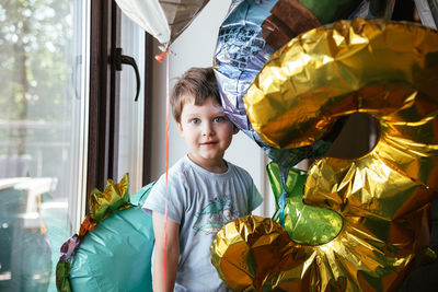 Cheerful birthday boy stands near the window