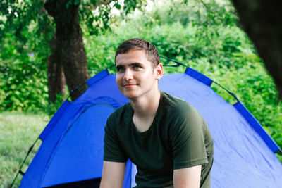 Portrait of young man sitting in tent