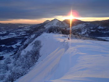 Snowcapped landscape against sky during sunset