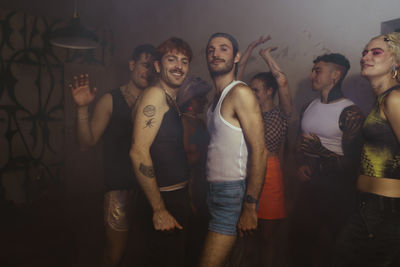 Smiling portrait of gay men clubbing with non-binary friends at nightclub