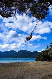 Low angle view of person paragliding on land against sky