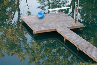 Wooden bench by lake against trees