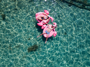 High angle view of people lying in inflatable rings on swimming pool during sunny day