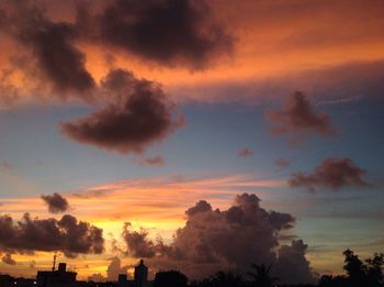 Low angle view of silhouette trees against dramatic sky