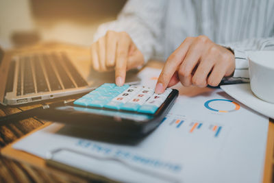 Midsection of businessman using calculator at table