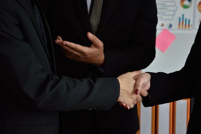 Midsection of business colleagues shaking hands