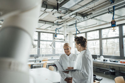 Happy senior scientist having discussion with colleague at laboratory