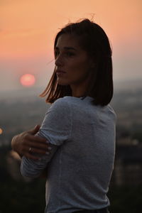 Woman standing against sky during sunset