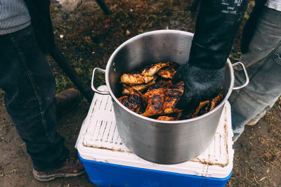 Low section of men with meat in container on field