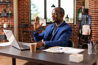 Businessman waving during video call at office