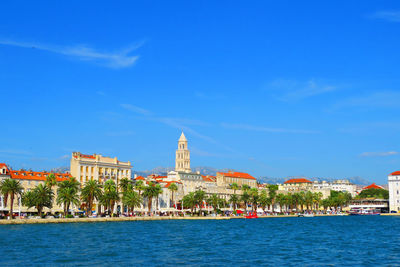 View of buildings at waterfront against blue sky