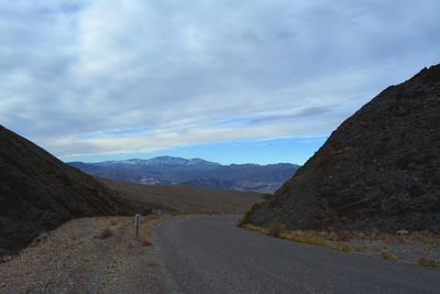 Road by mountains against sky