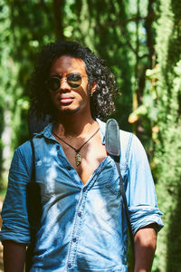 Portrait of young woman wearing sunglasses standing in forest