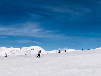 Woman skiing on snow covered land against sky