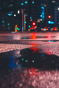 Surface level of wet road in illuminated city at night