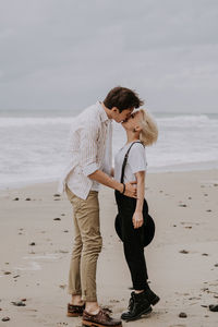 Young attractive couple having fun at he beach with a dog