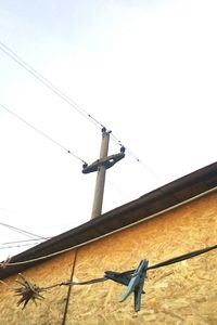 Low angle view of bird perching on electricity pylon against clear sky