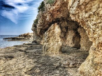 Rock formation on beach against sky