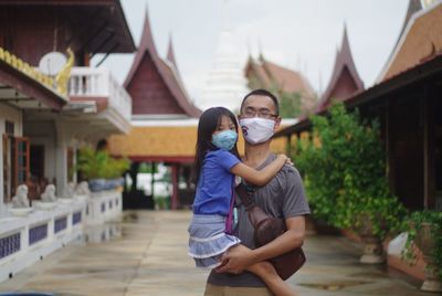 Man and woman with umbrella against building