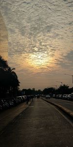 Road by city against sky during sunset