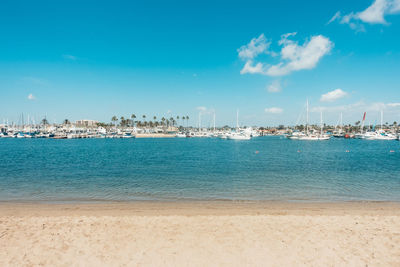 Boats moored at harbor against blue sky