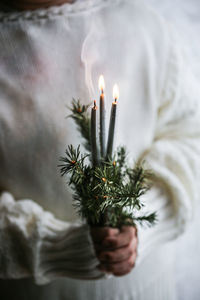 Close-up of woman holding burning candle during christmas