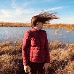 Woman tossing hair while standing by lake