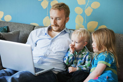 Father with daughter and son using laptop