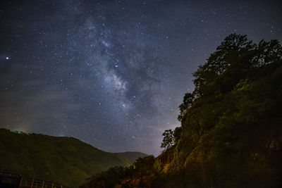 Scenic view of mountains against sky at night with galaxy 