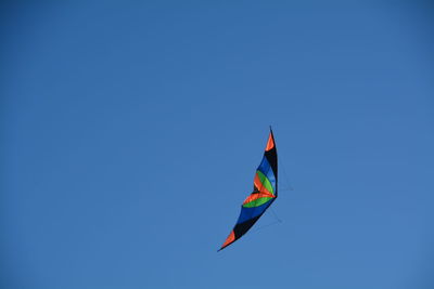 Low angle view of multi colored kite against clear blue sky