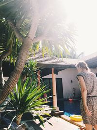 Woman standing by palm trees