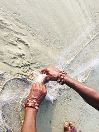 Low section of woman holding fishing net at beach