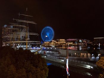 Light trails on illuminated city against sky at night