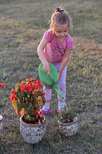 Girl watering plants while standing on grass