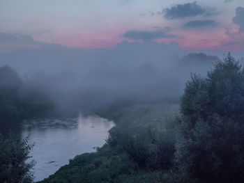 Scenic view of dubna river by trees against cloudy sky during sunset
