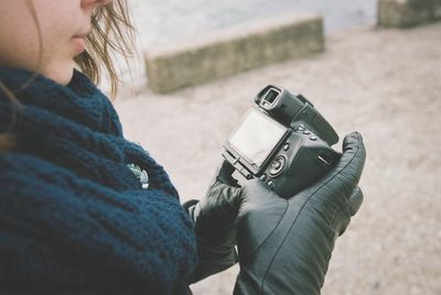 Midsection of woman holding camera outdoors